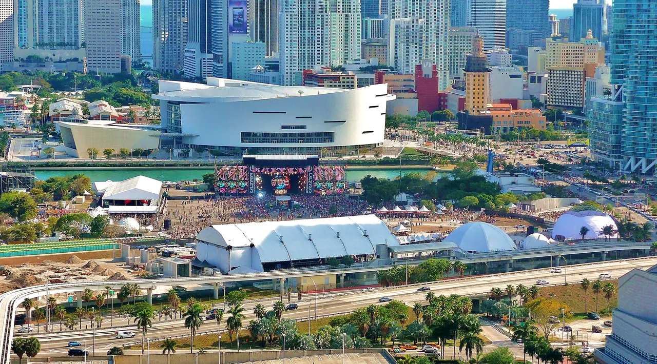 Ultra Music Festival's main stage and tents fill Bayfront Park beside the Kaseya Center, seen from above Biscayne Boulevard.