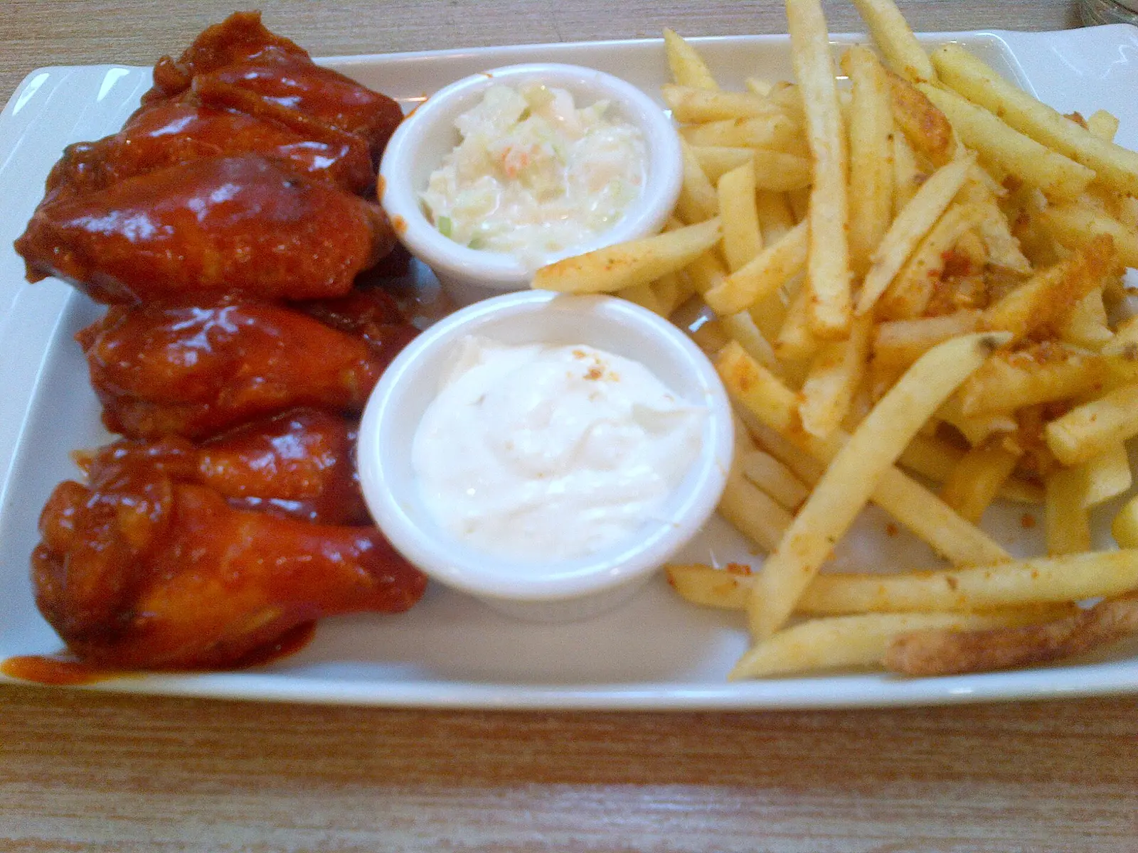 A plate of hot wings with fries and coleslaw. The photo was not taken at a Miami restaurant.